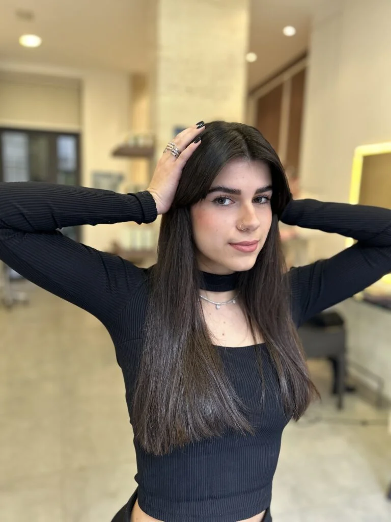 Coiffure femme aux cheveux noires dans un lumineux salon de coiffure; La lumière est dorée et elle une coupe avec une frange Rideau.